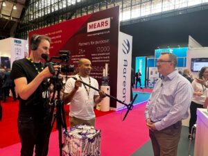 Andy Cameron-Smith from Unlock Net Zero being interviewed and videoed on the Sava exhibition stand at Housing 2022 in Manchester